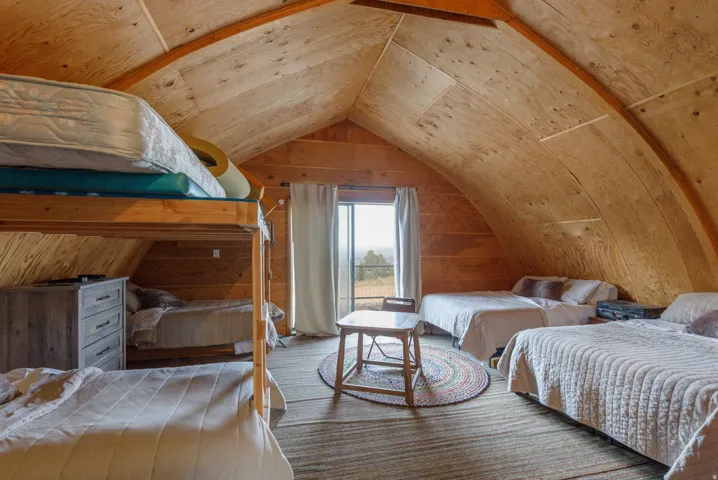 Vaulted wood-paneled ceiling with exposed wood beams, wood-finish flooring, and sliding glass doors