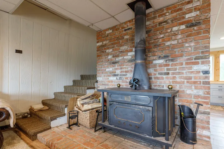 Freestanding wood-burning stove with a brick accent wall and a terracotta tile hearth