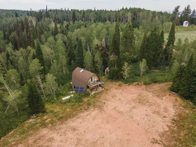 Dome-shaped residence featuring a brown shingle roof, wood siding, and a covered patio