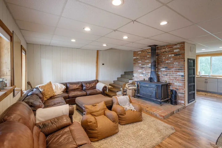 Living area featuring a brick accent wall with a black wood-burning stove on a raised brick hearth