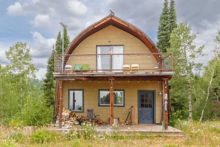 Two-story residence featuring a distinctive arched roofline and a second-story balcony with metal railing