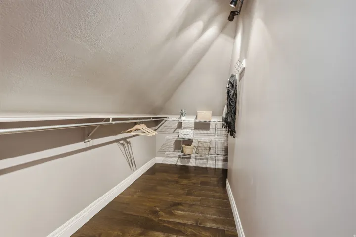Attic storage area featuring wood-finish flooring, track lighting, and built-in wire shelving
