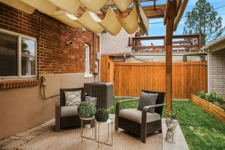Private patio with a pergola featuring a retractable shade canopy, brick exterior, and a manicured lawn