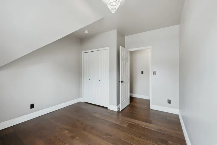 Spacious room featuring wood-finish flooring, light grey walls, and white trim