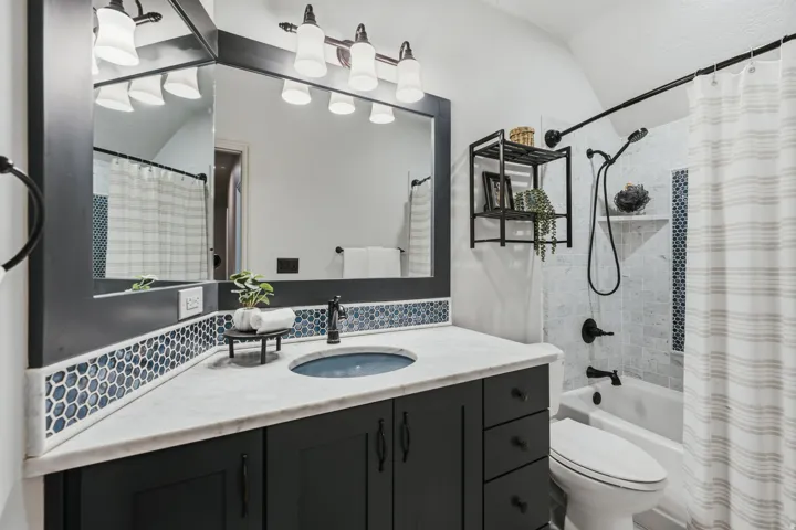 Bathroom featuring a single vanity with a white countertop, dark wood-finish cabinetry, and a blue hexagonal tile backsplash