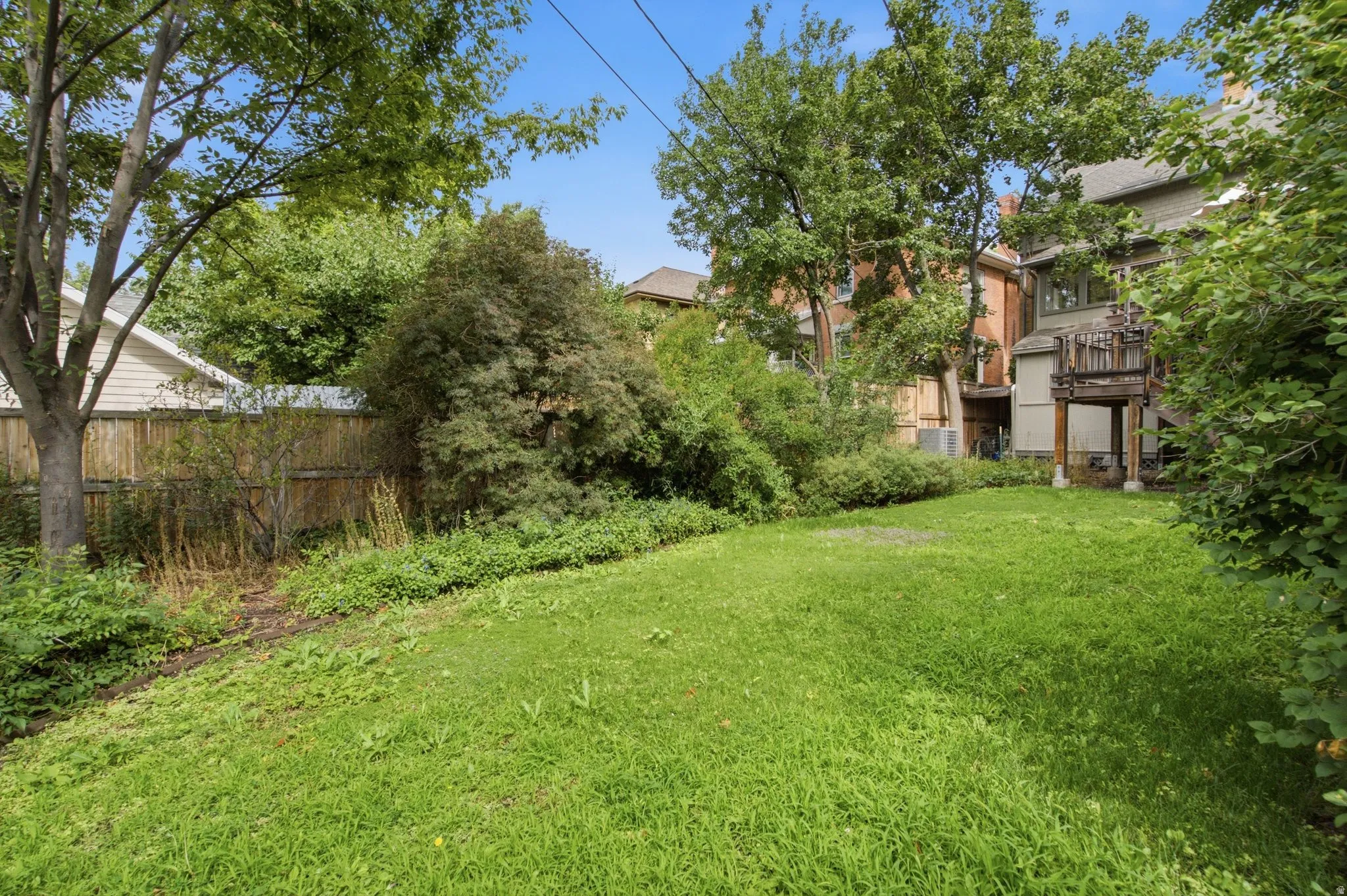 Expansive green lawn with mature trees and established perimeter landscaping