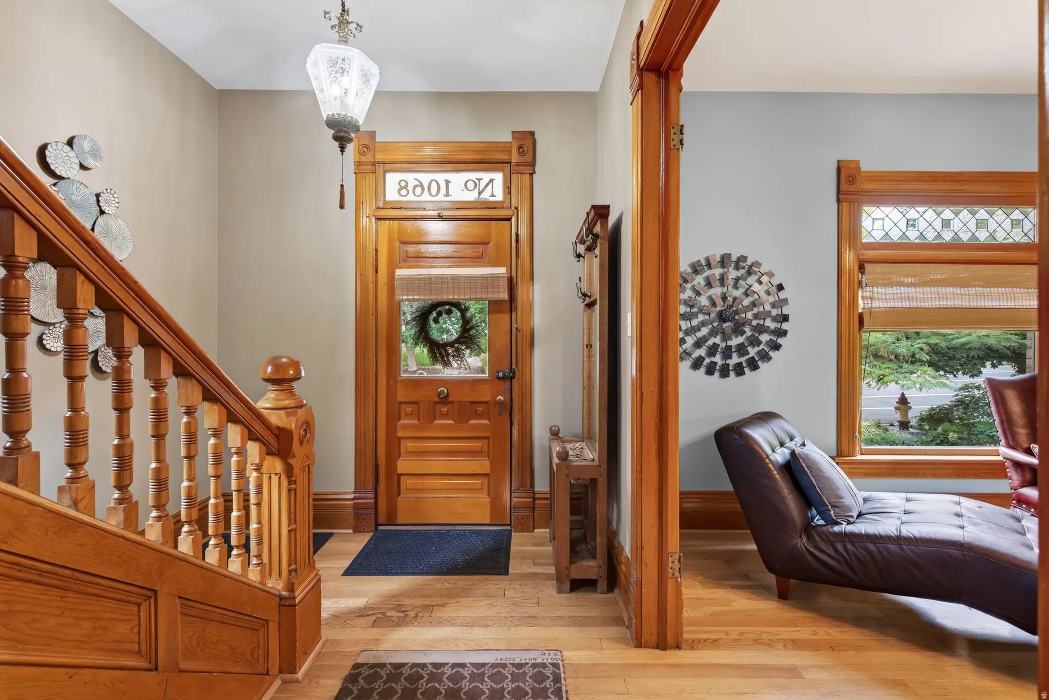 Entryway featuring wood-finish flooring, a detailed wooden staircase, and a solid wood front door with a glass insert