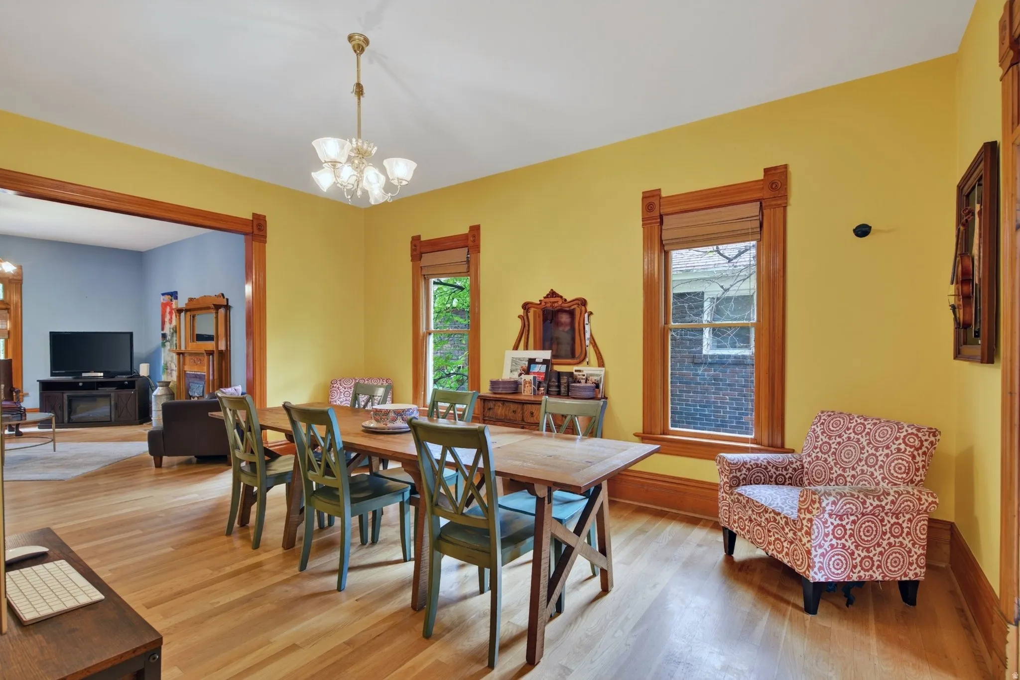 Spacious dining area featuring wood-finish flooring, a chandelier, and two windows with wood trim