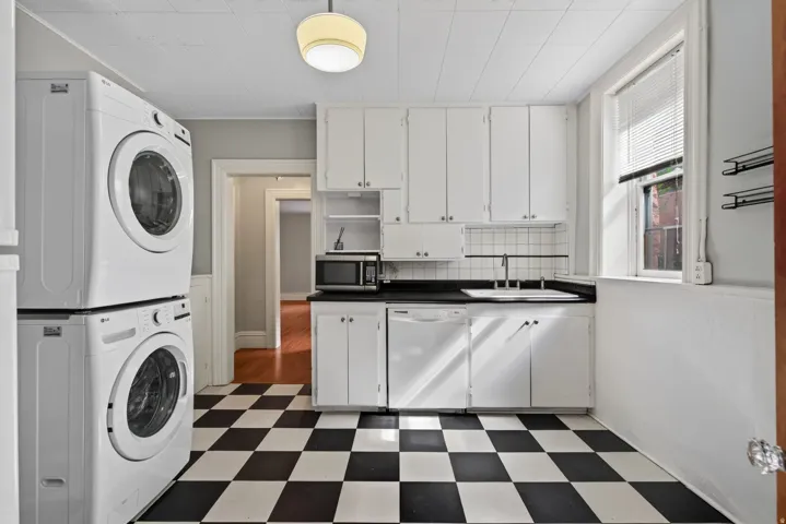 Kitchen with white cabinetry, black countertops, and a white tile backsplash
