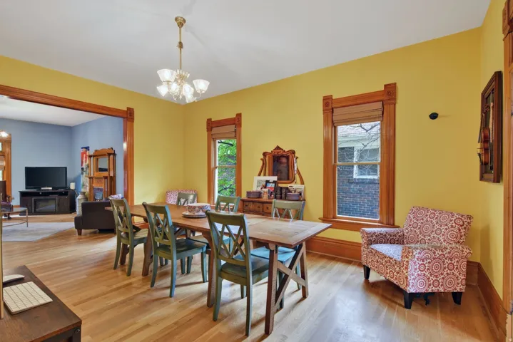Spacious dining area featuring wood-finish flooring, a chandelier, and two windows with wood trim