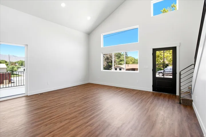 Spacious room with high vaulted ceilings, recessed lighting, wood-finish flooring, and multiple windows providing natural illumination