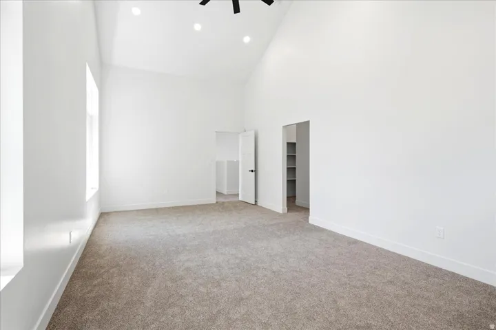 Spacious room featuring vaulted ceilings, recessed lighting, and light brown carpeting