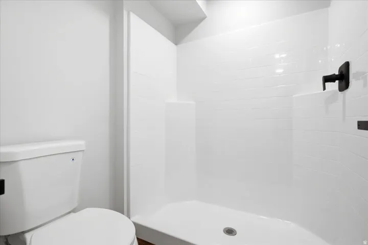 Contemporary shower stall featuring white subway tile surround, matte black fixtures, and a clean white base