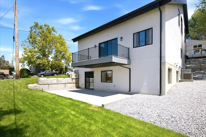 Modern white stucco exterior with black-framed windows and a balcony featuring black railings