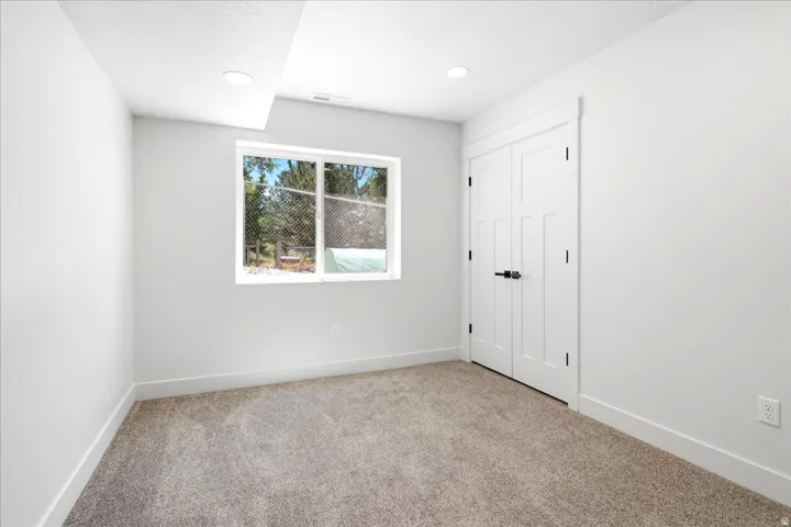 Windowed interior space featuring light gray carpet flooring and white walls
