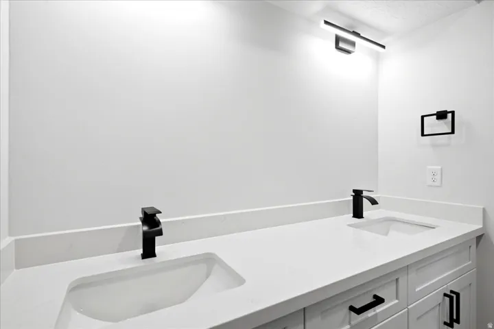 Double vanity featuring integrated sinks, white countertops, and matte black fixtures
