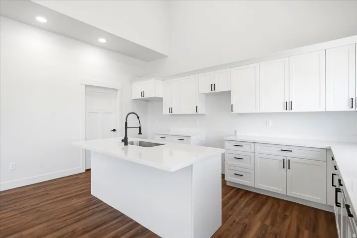Modern kitchen featuring a central island with an undermount sink and matte black faucet