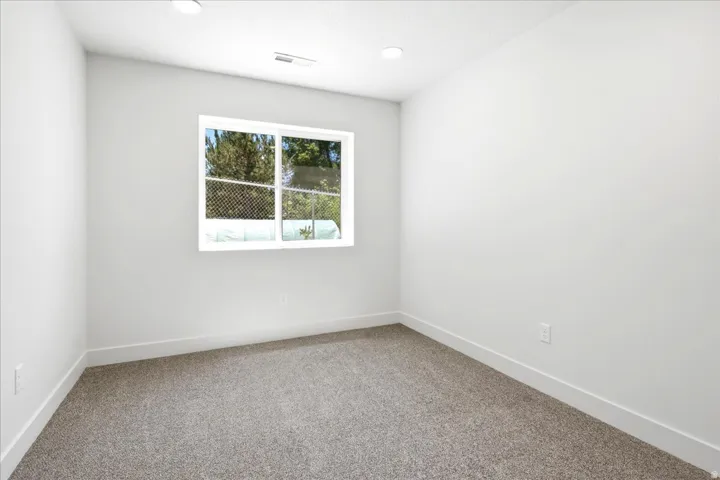 Bright room featuring a large window, recessed lighting, neutral paint, white trim, and plush carpeting