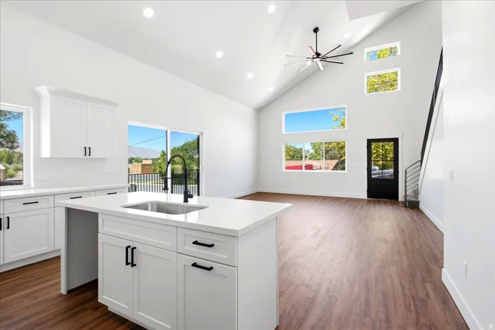Open-concept kitchen and living area featuring a vaulted ceiling and wood-finish flooring