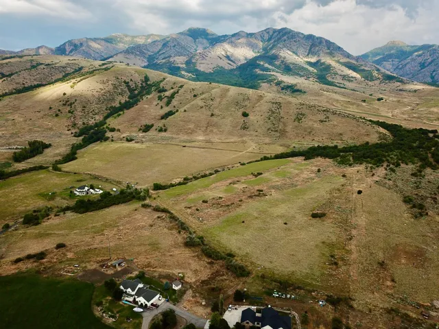 Expansive landscape featuring distant mountains and rolling hills with scattered greenery