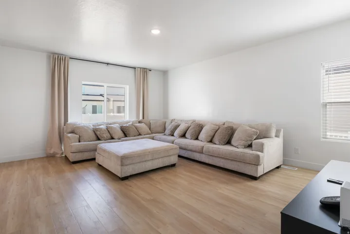 Spacious living area featuring light wood-finish flooring, white walls, and recessed lighting