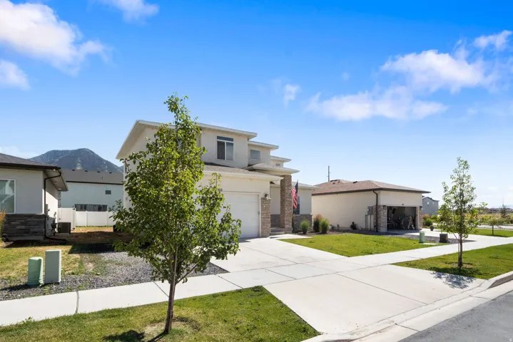 Contemporary two-story residence featuring a two-car garage, stone accents on the facade, and a paved driveway