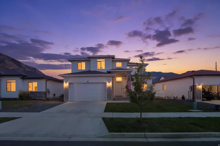 Modern two-story residence featuring a clean white exterior, stone accents, a two-car garage, and a concrete driveway