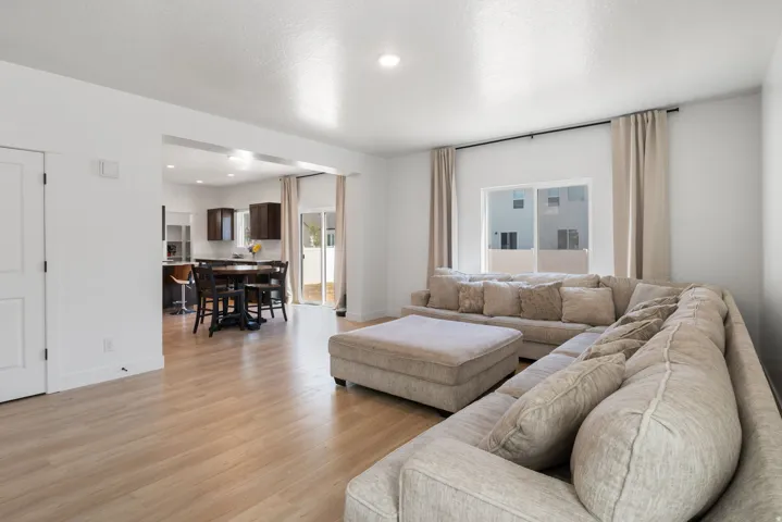 Open-concept living space featuring light wood-finish flooring, recessed lighting, and a white interior door