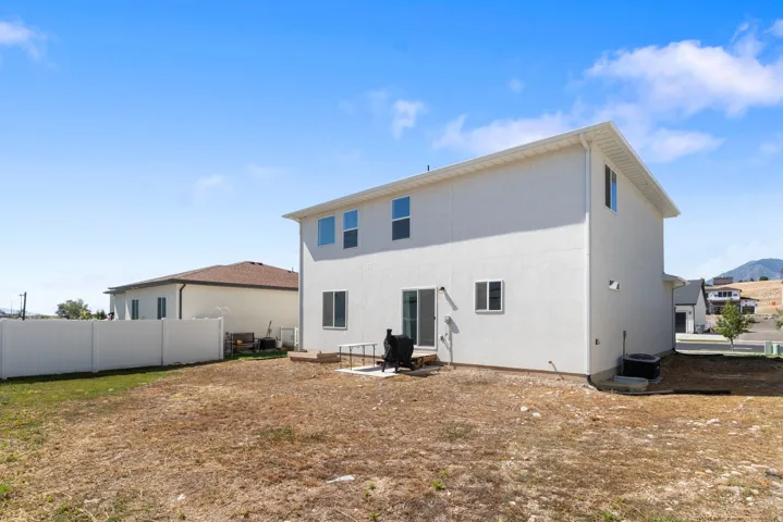 Rear exterior featuring a sliding glass door, a concrete patio, white stucco siding, and a white vinyl privacy fence