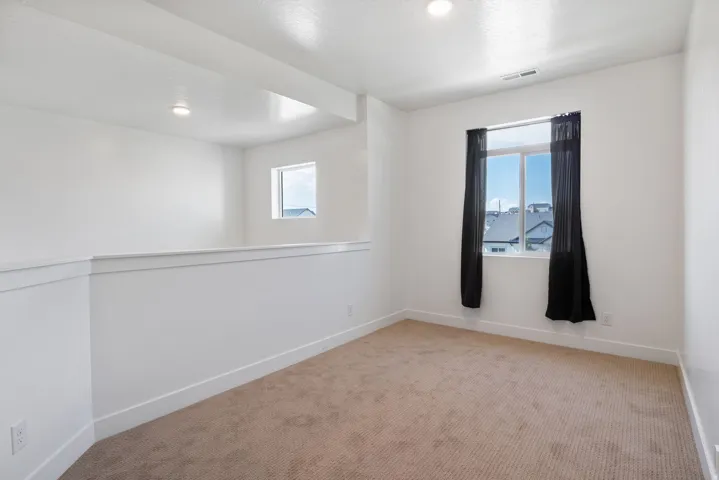 Carpeted room featuring white walls, recessed lighting, and a single window with dark curtains