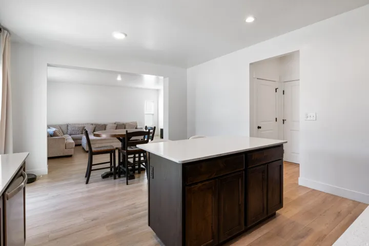 Kitchen island featuring a white countertop and dark wood-finish cabinetry, complemented by light wood-finish flooring