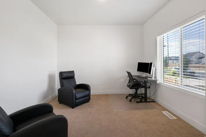 Carpeted room featuring a large window with horizontal blinds, white baseboards, and a ceiling light fixture