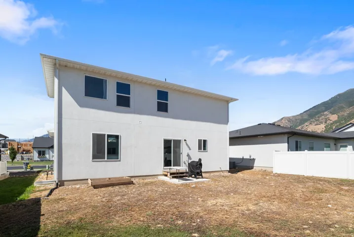 Rear exterior showcasing a white stucco finish, multiple windows, and a sliding glass door