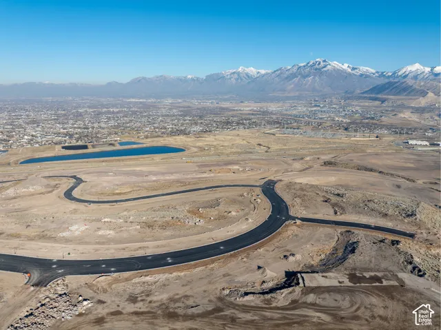New road infrastructure in a developing area, featuring clear blue retention ponds and distant snow-capped mountains