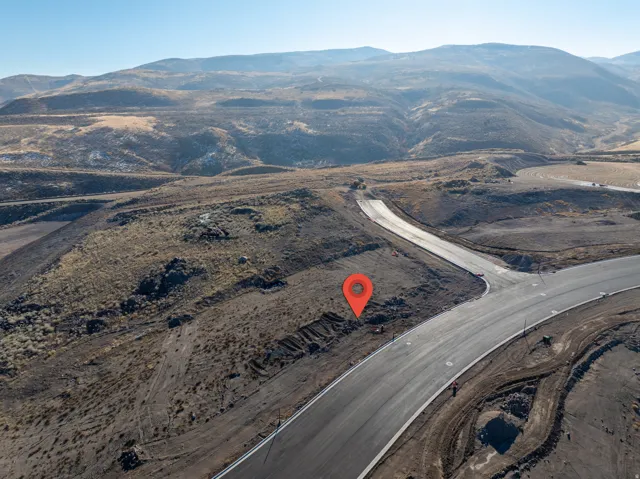 Property features a newly paved road, partially developed land, and a mountain backdrop