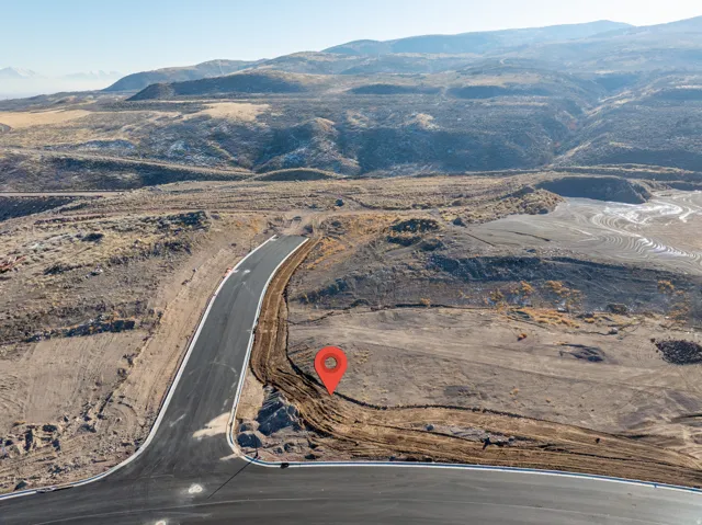 Newly paved asphalt road with defined white road striping and surrounding undeveloped land