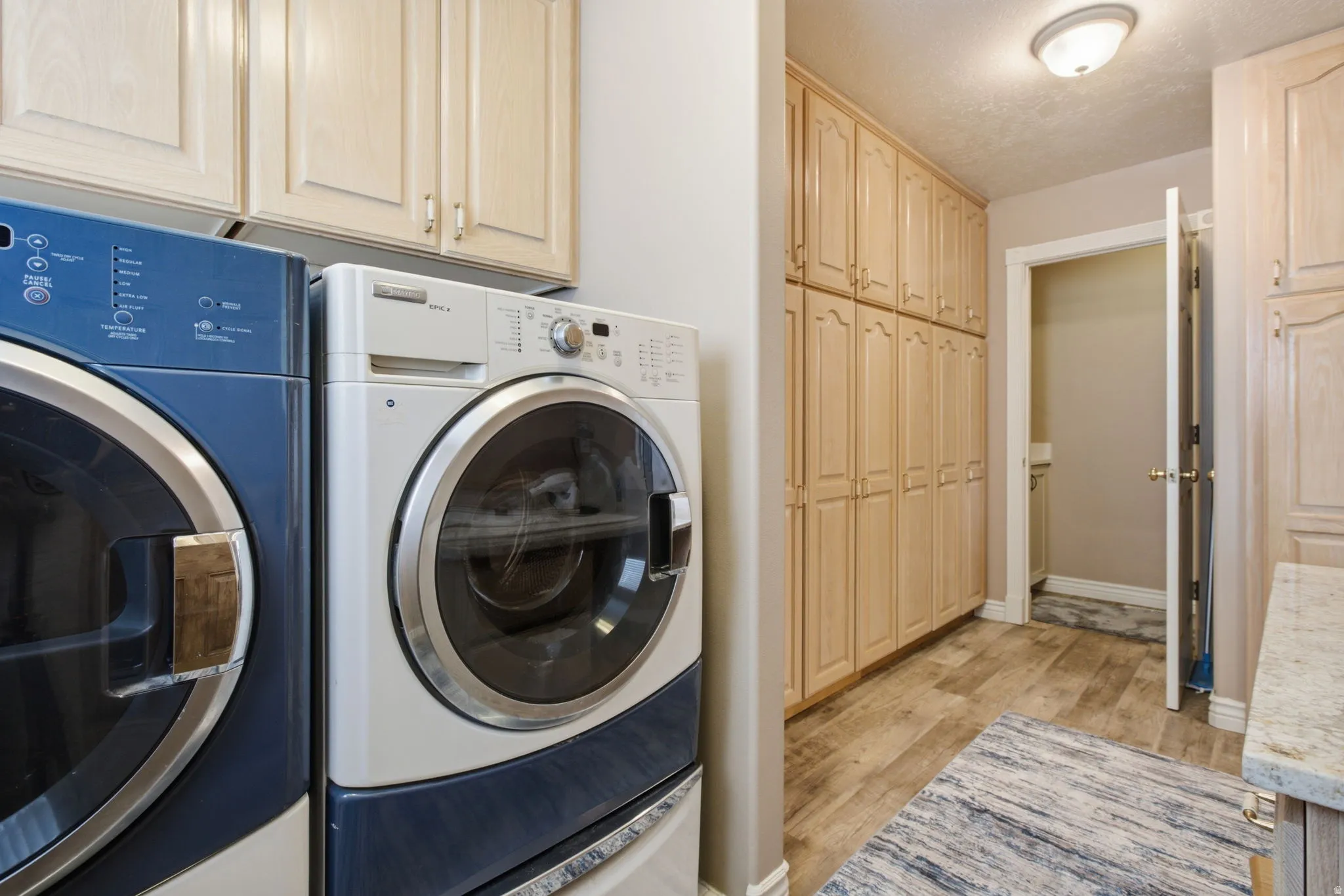 Functional laundry area featuring wood-finish flooring and extensive built-in cabinetry