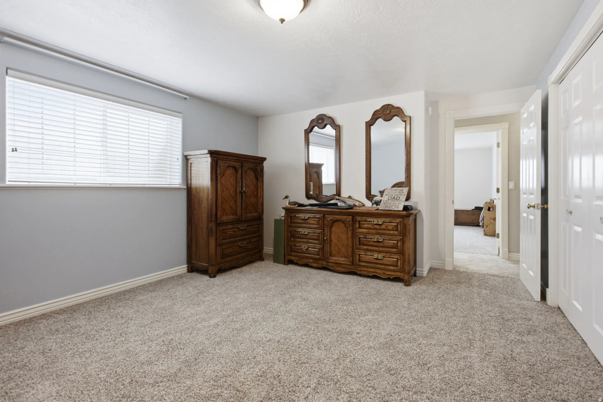 Carpeted room featuring a window with horizontal blinds, neutral wall colors, and white trim