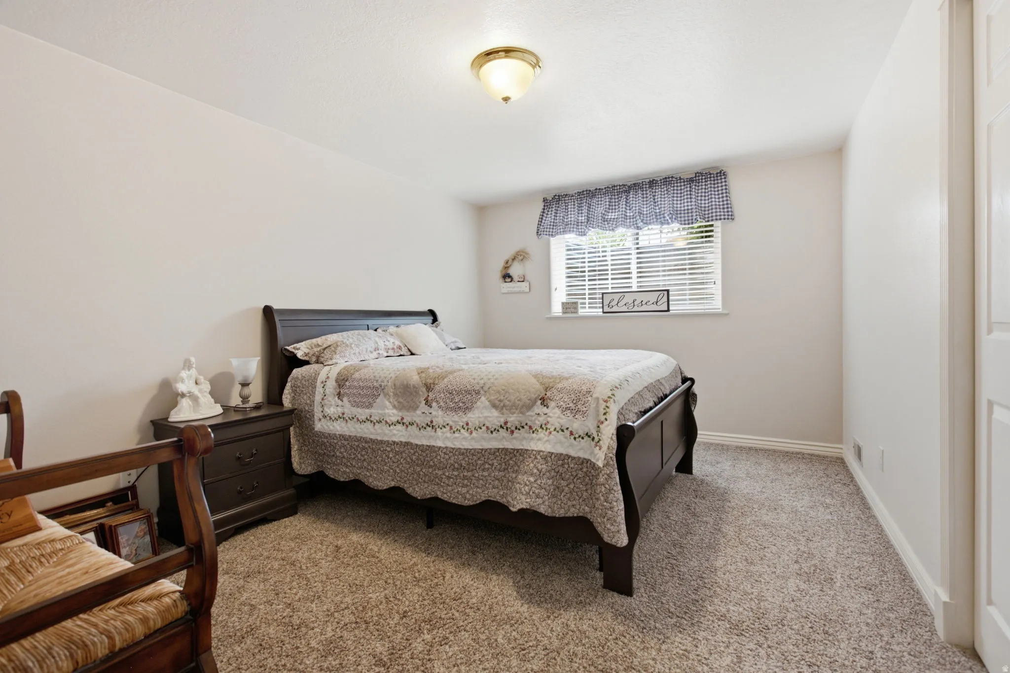 Carpeted room featuring a single window with blinds, light-colored walls, and a ceiling-mounted light fixture