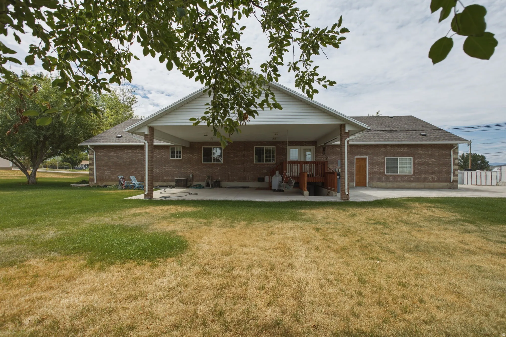 Brick exterior featuring a covered patio, wood deck, and multiple windows