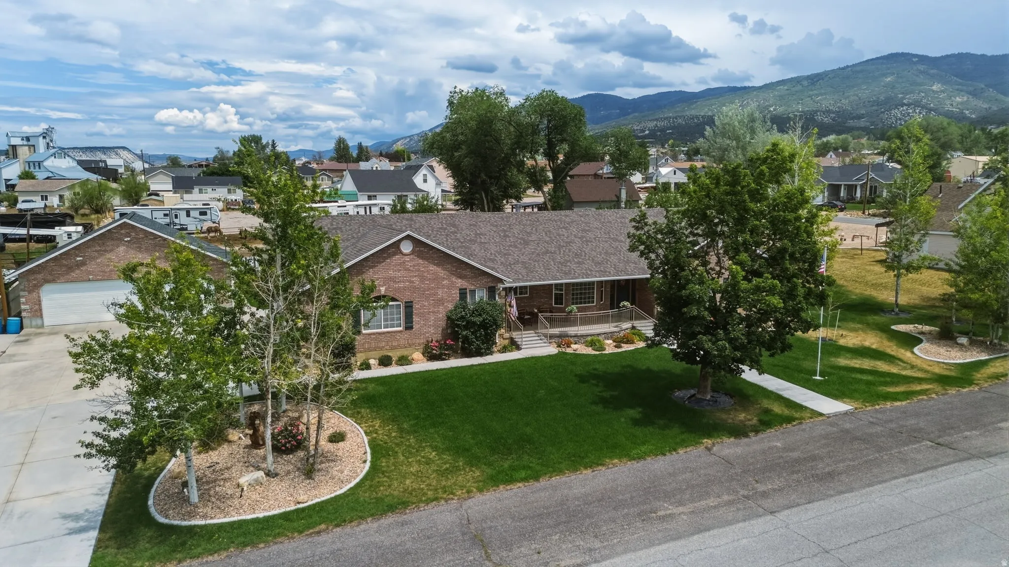 Brick ranch-style residence featuring an attached two-car garage, established landscaping, and a covered front porch