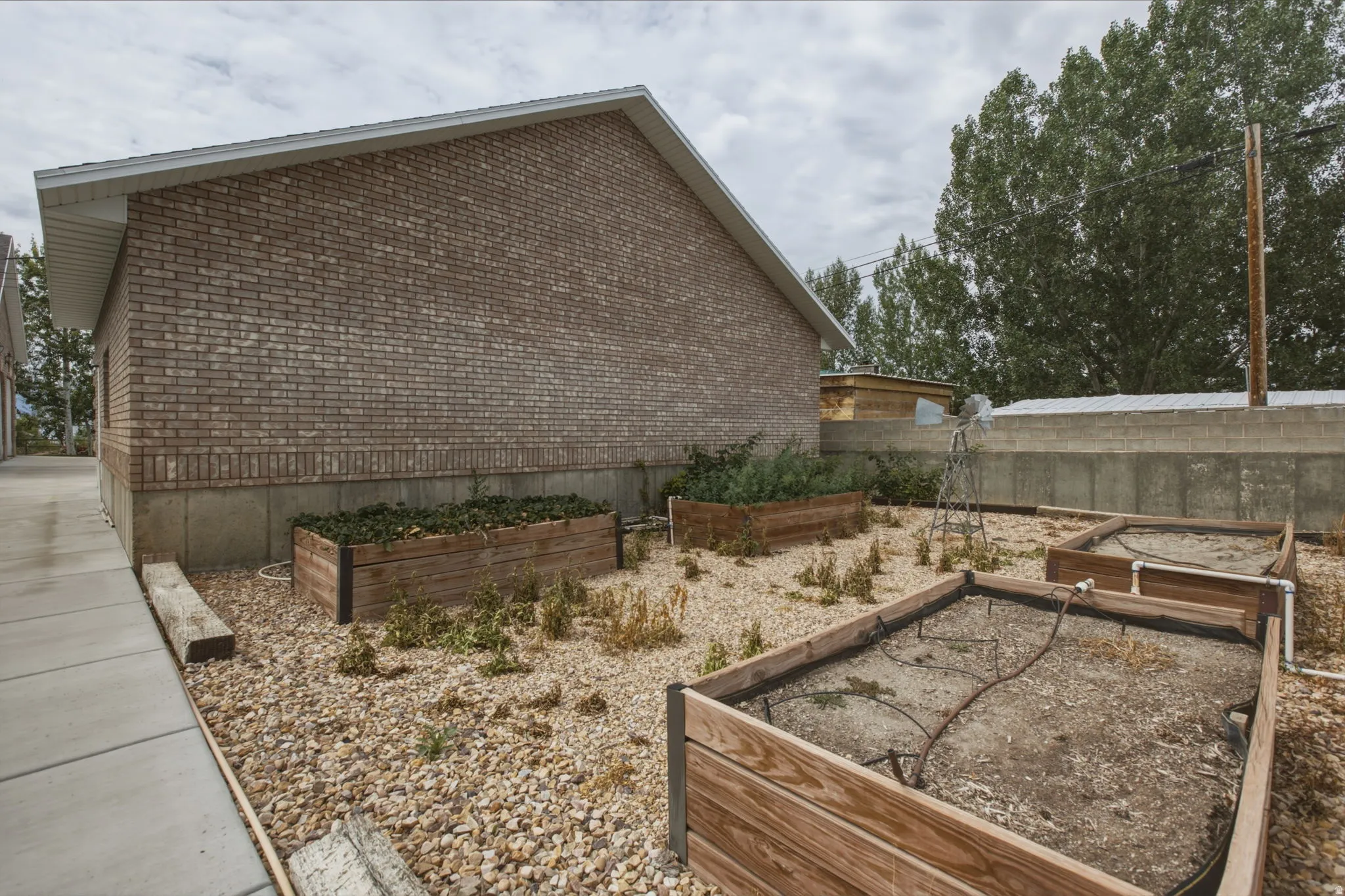 Brick exterior with a gable roofline, concrete foundation, and a concrete pathway
