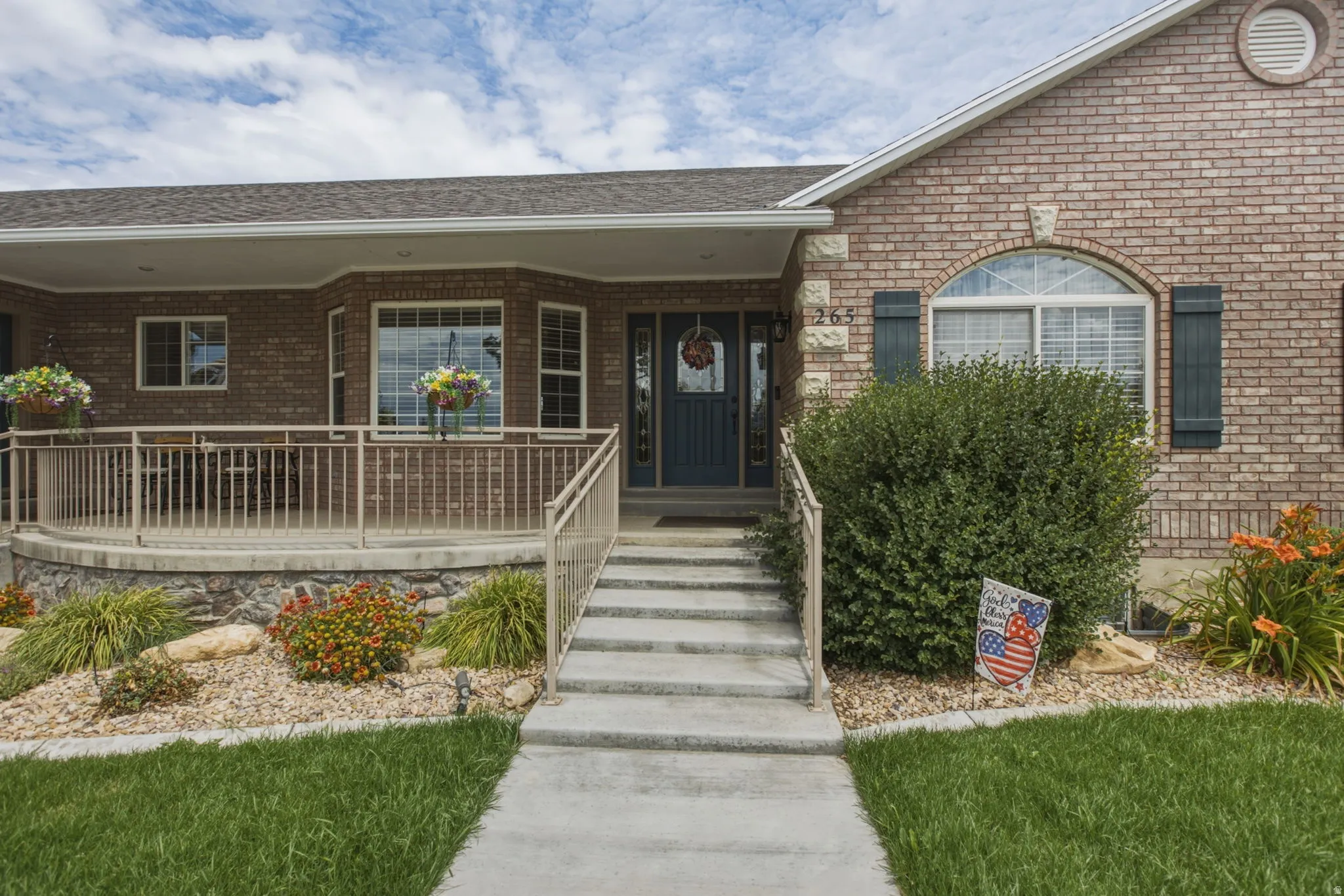 Brick exterior featuring a covered front porch with railings, bay window, and a dark entry door