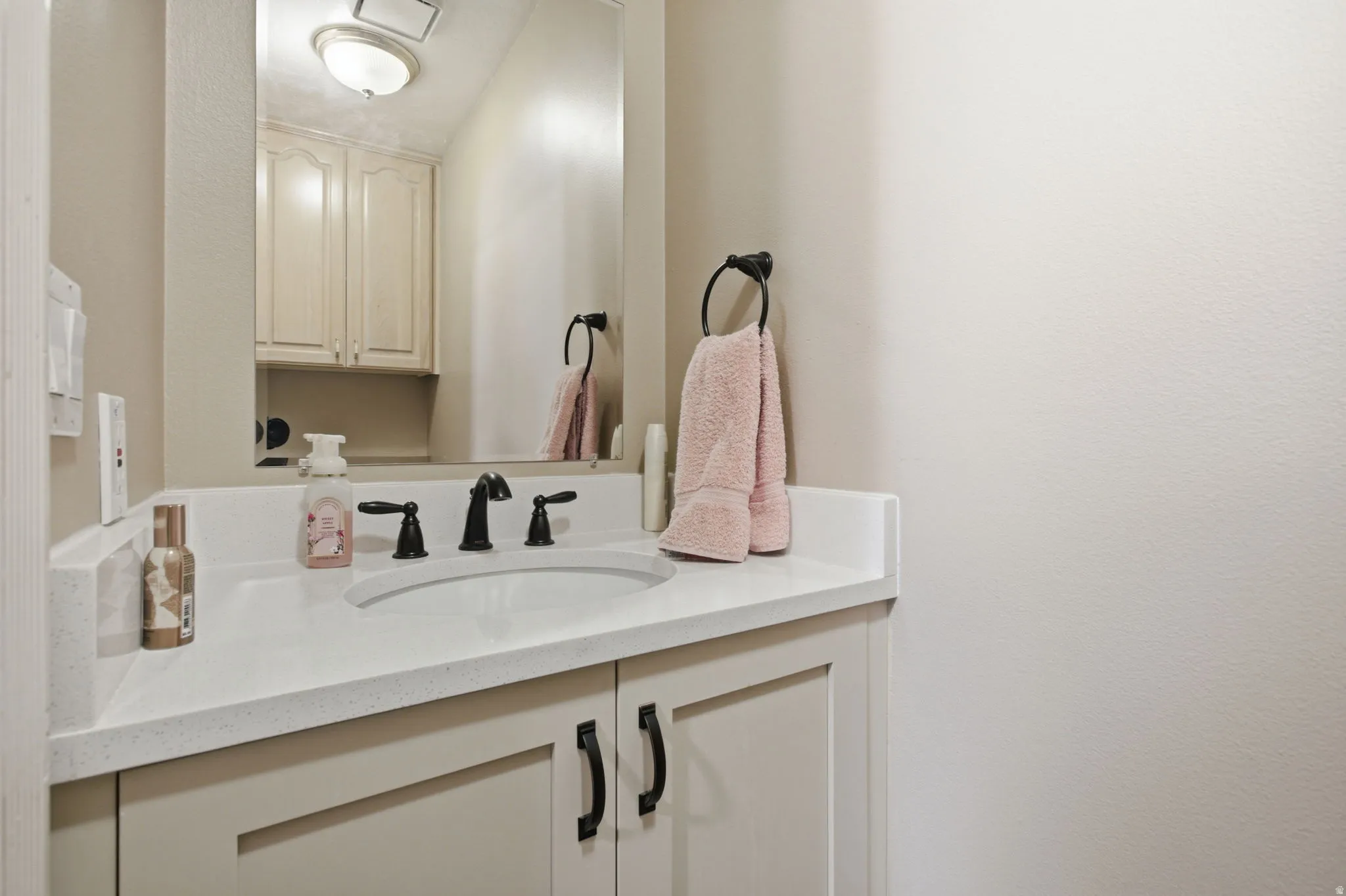 Powder room vanity featuring a light-toned countertop, undermount sink, and matte black faucet