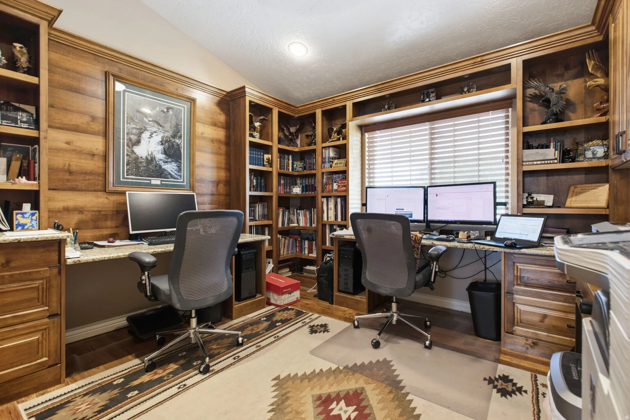Custom-built office featuring extensive wood cabinetry, integrated shelving, and granite countertops