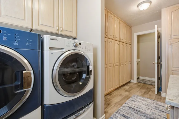 Functional laundry area featuring wood-finish flooring and extensive built-in cabinetry