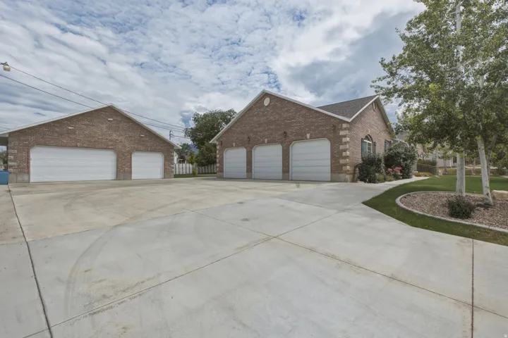 Expansive concrete driveway featuring a main residence with a three-car garage and a detached structure with a two-car garage