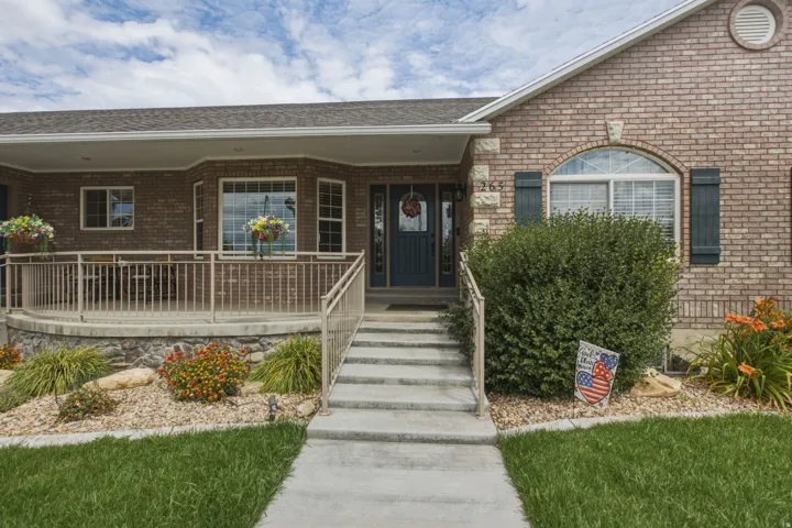 Brick exterior featuring a covered front porch with railings, bay window, and a dark entry door