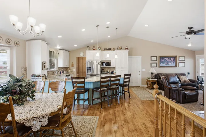 Open-concept living area featuring wood-finish flooring, vaulted ceilings, and recessed lighting