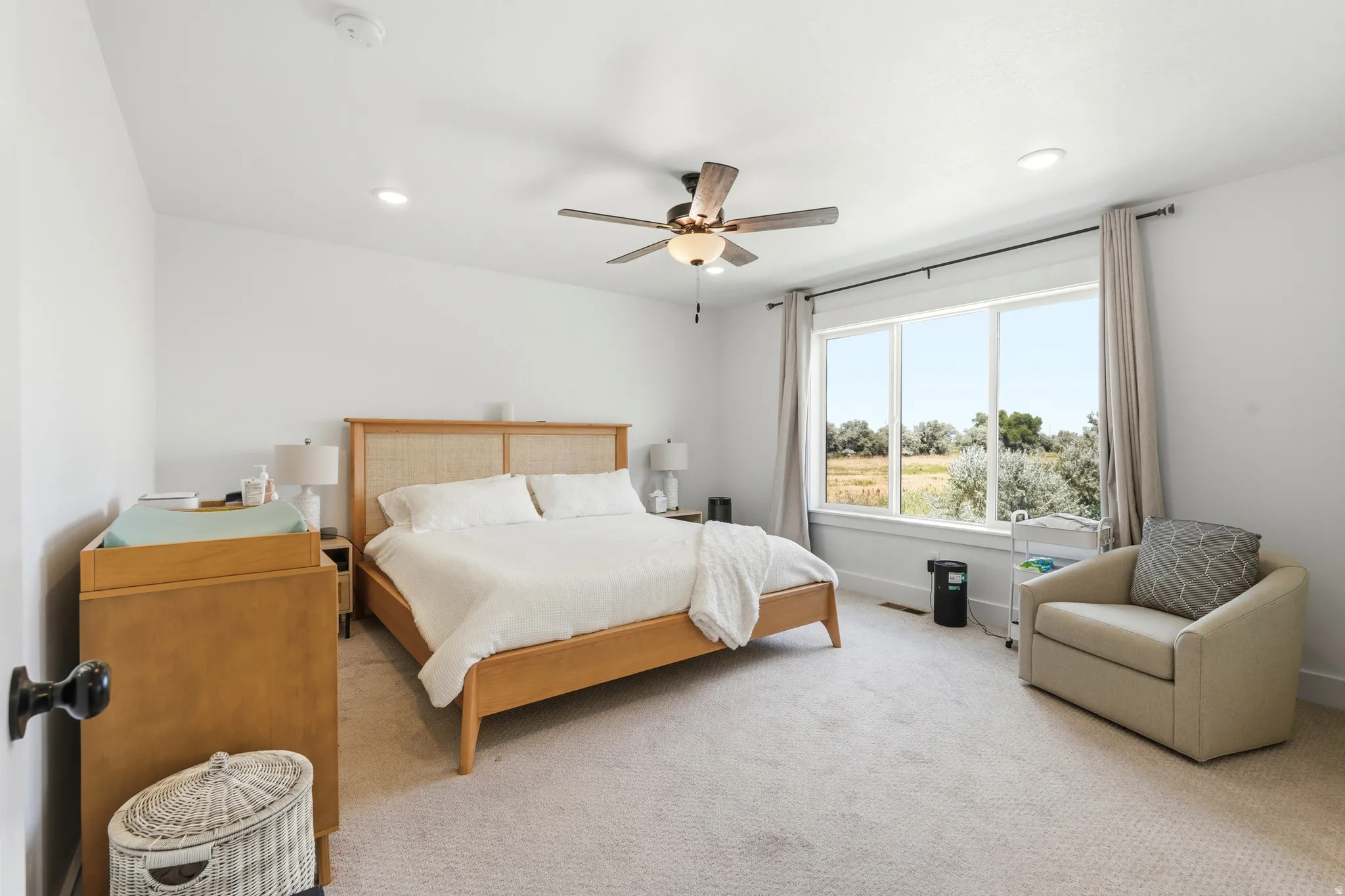 Bright bedroom featuring a large picture window, recessed lighting, and a ceiling fan